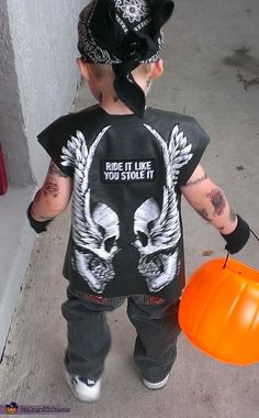 a young boy with tattoos holding an orange frisbee