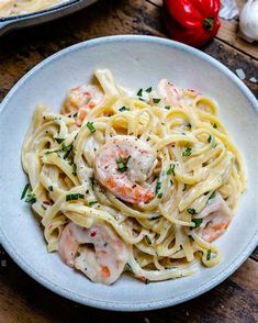 pasta with shrimp and parmesan cheese in a white bowl on a wooden table