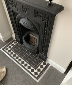 an ornate fireplace in the corner of a room with black and white tiles on the floor