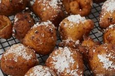 powdered sugar covered donuts cooling on a rack