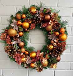 a christmas wreath on a brick wall with pine cones, ornaments and other holiday decorations