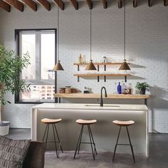 an open kitchen with three stools next to the counter