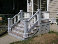 a set of stairs leading up to a house with white railings and balconies