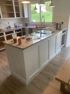 a large kitchen with an island in the middle and two pendant lights hanging from the ceiling