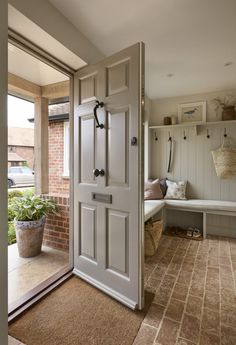 an open door leading to a sitting area with potted plants on the outside wall