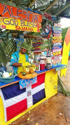 a man standing behind a food stand selling bananas and other foods on the side of the road