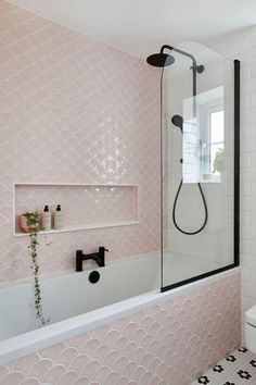 a bathroom with pink and white tiles on the walls, black fixtures and a bathtub