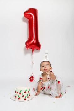 a baby sitting in front of a cake with the number one on it