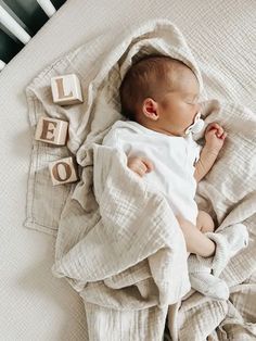 a baby is sleeping on a blanket with blocks that spell out the word love in front of him