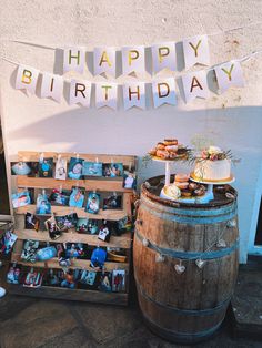 a birthday cake and cupcakes are on display in front of a wooden barrel