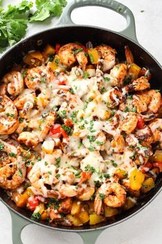 a skillet filled with shrimp, peppers and cheese on top of a white table