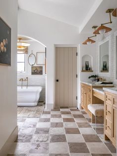 a bathroom with a checkered tile floor and white tub in the corner, along with an arched doorway leading to another room