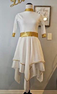 a white dress with gold trims is on display in front of a sign that says do