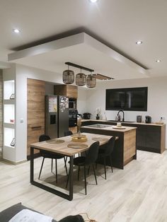 an open kitchen and dining room area with wood flooring, white walls and ceiling