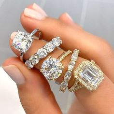 a woman's hand holding three different rings with diamonds on each ring and an engagement ring in the middle