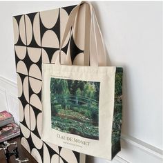 a canvas bag hanging on the wall next to a book case with a painting of a bridge and water lilies