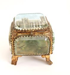 Find an antique French jewellery / Ormolu box. The box is in the shape of a casket with bevelled glass Size: W- 7.2 cm, D- 7 cm, H- 7.2 cm  Condition: The interior is a little discoloured  Fabulous antique box, find more unique boxes in my shop https://www.etsy.com/uk/shop/perdisjewellerybox?search_query=antique+box French Souvenirs, Crystal Jewelry Box, Paris Souvenirs, Glass Trinket Box, Back Painted Glass, Art Nouveau Antiques, Jewelry Casket, Back Painting, French Jewelry