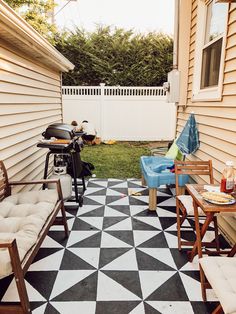 a black and white checkered patio with bbq, chairs, table and grill