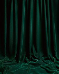 an image of a dark green curtain that is drapes open to reveal the light