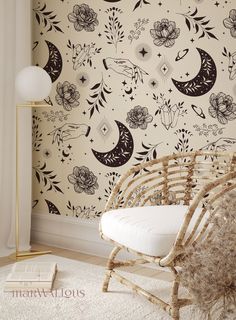 a white chair sitting in front of a wall with black and white flowers on it