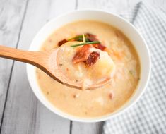 a wooden spoon filled with soup on top of a table