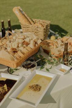 a table with bread and other food items on it, including wine bottles in the background