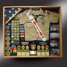 an army uniform is displayed in a shadow box with badges and other items on it