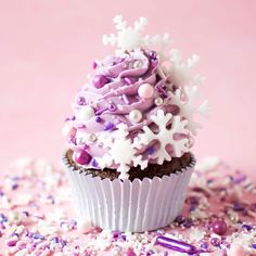 a cupcake with purple frosting and sprinkles sitting on top of it