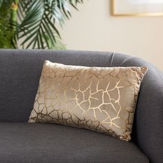 a giraffe print pillow sitting on top of a gray couch next to a potted plant