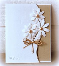 a card with white flowers on it and a brown ribbon tied around the bottom corner