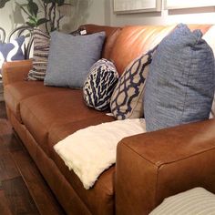 a brown couch with blue and white pillows on it