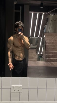 a man taking a selfie in front of a mirror with his shirt off and no shirt on