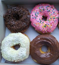 six donuts in a box with sprinkles, chocolate, and pink