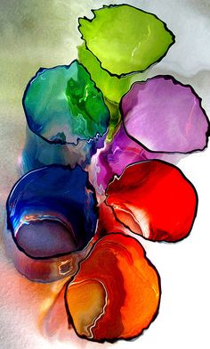 several different colors of paint sitting on top of each other in a vase with one green leaf