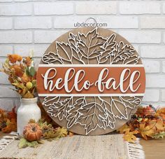 a wooden sign that says hello fall with leaves and pumpkins in front of it