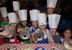 a group of children in chef hats holding up plates