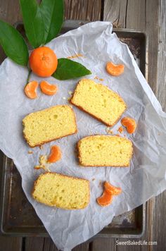 several pieces of cake sitting on top of a tray next to an orange and some leaves