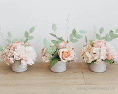 three vases filled with flowers on top of a wooden table