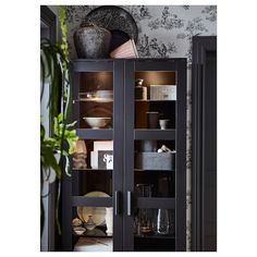 a black cabinet with glass doors and shelves filled with dishes, cups and vases