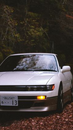 a white car is parked in the woods