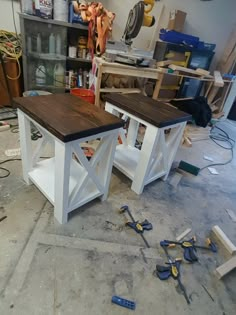 two wooden tables sitting on top of a floor in a room filled with tools and supplies