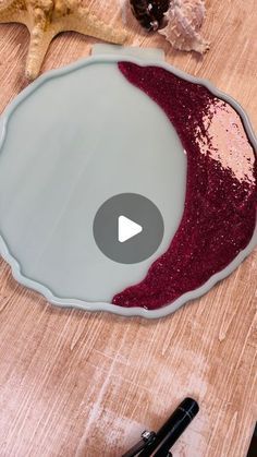 a wooden table topped with a bowl filled with red liquid next to a starfish