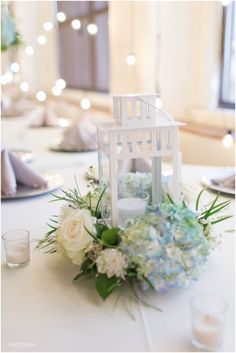 a white table topped with a vase filled with flowers and a candle holder on top of it