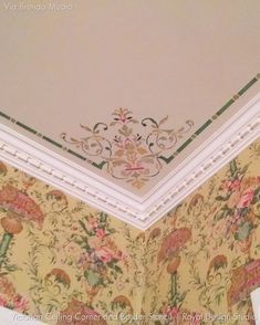 the corner of a room with floral wallpaper and decorative trimming on the ceiling