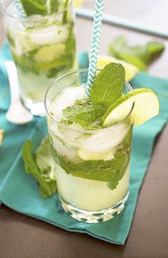 three glasses filled with cucumber and limeade on top of a white table