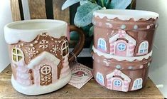 two coffee mugs sitting next to each other on a wooden table near a potted plant