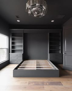 an empty bedroom with built - in bookcases and a chandelier hanging from the ceiling