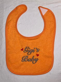 Gigi's Baby custom embroidered bib. "Gigi" can be changed to Grandma, Nana, Grandpa, etc. Thread colors can be changed to fit your needs. Please leave me a note, at the time of purchase, to tell me of any changes. Terry Cloth Feeder Bibs Hook and loop fastener Cotton/polyester Each bib measures 8.25" W x 9" L from top of shoulder (7" L from center neck opening). Occasionally, I have to purchase the bibs from different manufacturers so the size may vary a bit Machine wash warm, tumble dry low  Do not use chlorine bleach (the embroidery thread will fade) When you get your bib you may see remnants of a clear plastic film. This is water soluble stabilizer and it will dissolve on the first wash. The white mesh fabric on the back of the bib is water soluble stabilizer also. It may take 2-3 washe Personalized Cotton Bib As Gift, Embroidered Cotton Bib, This Is Water, Plastic Film, Thread Colors, Have A Blessed Day, White Mesh, Hook And Loop, Terry Cloth