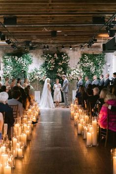 a bride and groom standing at the end of their wedding ceremony with candles in front of them