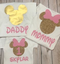 two t - shirts with gold and pink mickey mouse heads on them, one says daddy mommy and the other says skylar